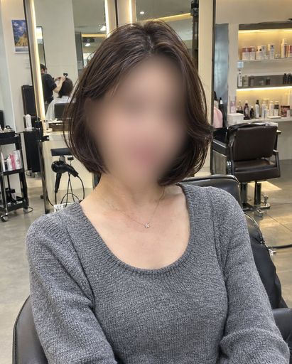 어깨 위로 떨어지는 레이어드 단발을 한 여성의 미용실 원본 사진(얼굴 블러 처리)